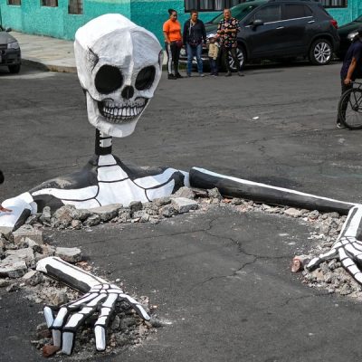 A girl touches a huge cardboard skull made by artisans in a street in the Tlahuac neighborhood, in Mexico City on October 28, 2019, ahead of the Day of the Dead celebrations. (Photo by Pedro PARDO / AFP) (Photo by PEDRO PARDO/AFP via Getty Images)